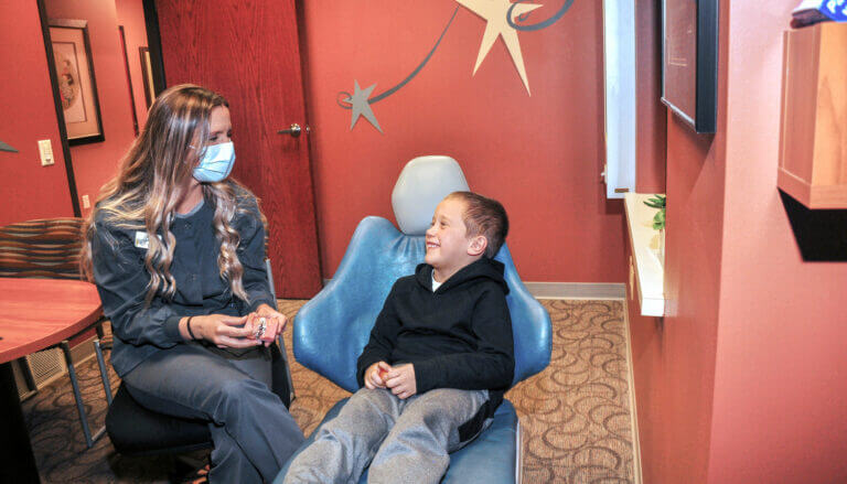 Dental hygienist showing a smiling child a dental mold